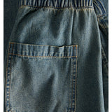 Baglomme af denimshorts med elastisk talje ses tæt på, viser denimvævningens blå farve og robuste syninger i et enkelt, afslappet design.
