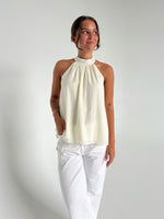 Modelfoto af pige der bærer en hvid Whitley halternec top, samt hvide Nanna jeans. Alt fra BySofieSønderby