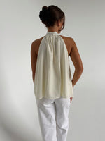 Modelfoto af pige der bærer en hvid Whitley halternec top, samt hvide Nanna jeans. Alt fra BySofieSønderby