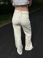 Modelfoto af pige i cremefarvede Arianna jeans og hvid top. Alt er fra BySofieSønderby