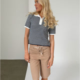 Modelfoto af pige iklædt ASHLEY polo, navy og AVERY jorts, sand - begge fra BySofieSønderby