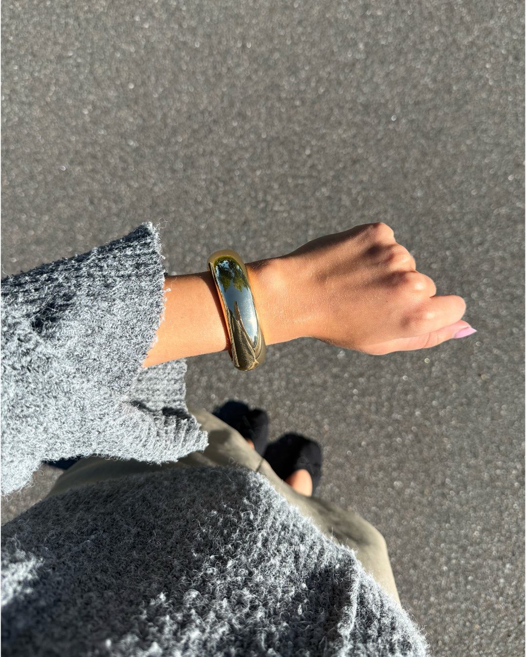 Modelfoto af en Avani guld armbånd. Baggrund er grå. Fra BySofieSønderby