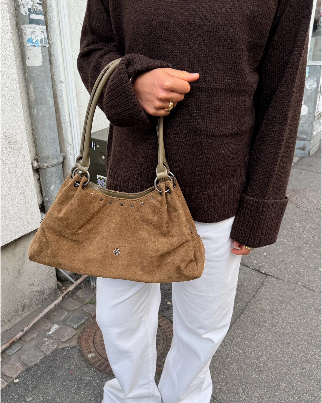 Modelbillede af pige der holder brun AYLANI taske på armen. Fra BySofieSønderby.