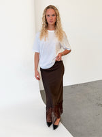 Modelfoto af pige i brun BILLIE nederdel, samt hvid t-shirt. Alt er fra BySofieSønderby.