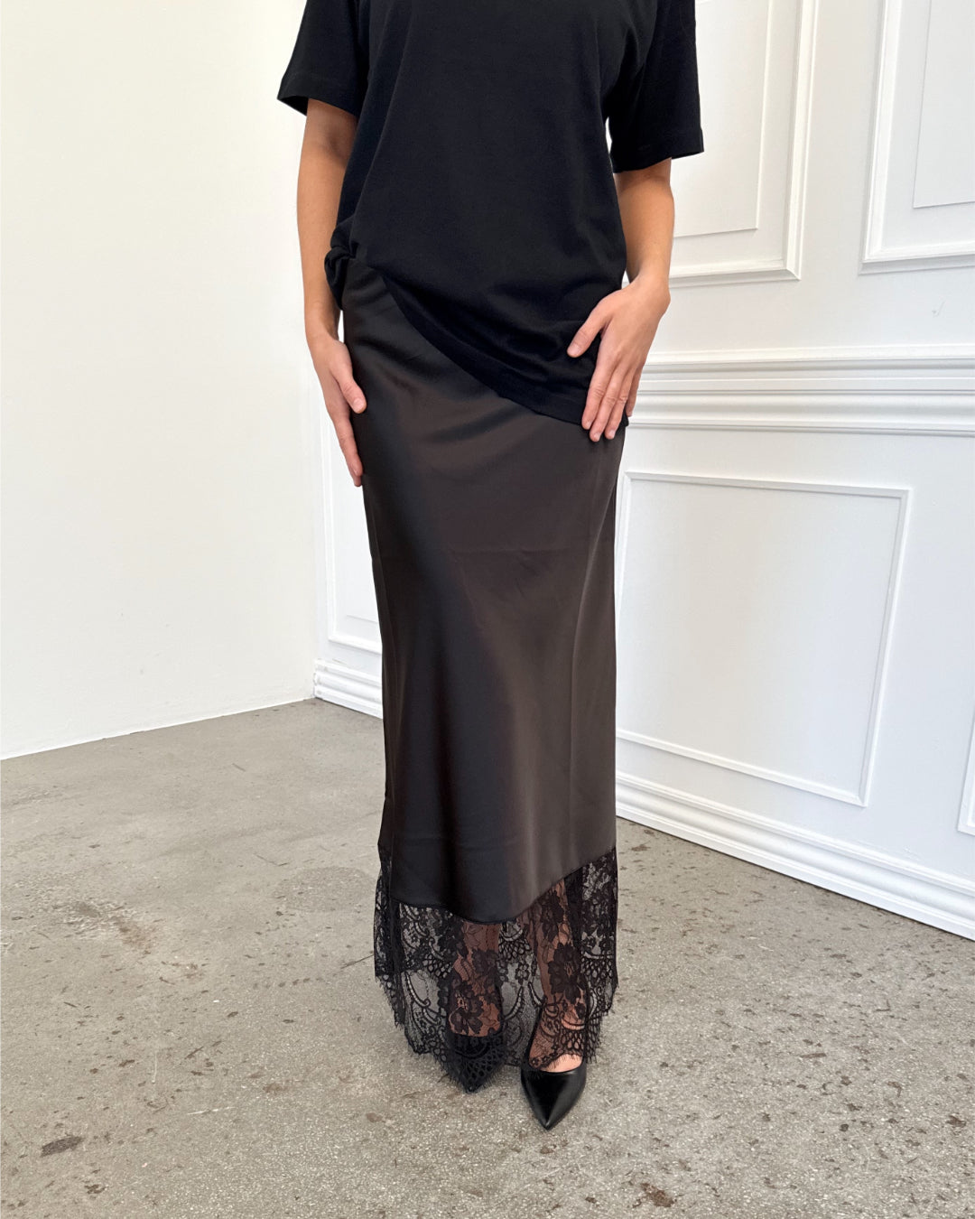 Modelfoto af pige i sort BILLIE nederdel, samt sort t-shirt. Alt er fra BySofieSønderby.