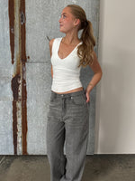 Modelfoto af pige der bærer Blakely top i hvid, samt grå Nanna jeans. Alt fra BySofieSønderby