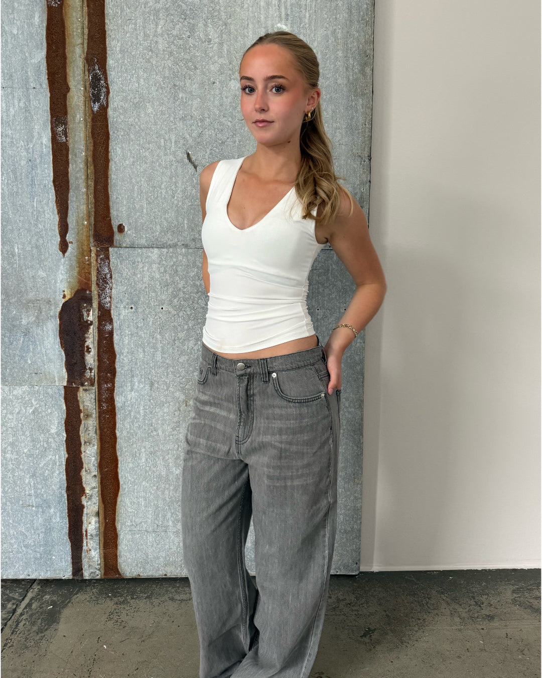 Modelfoto af pige der bærer Blakely top i hvid, samt grå Nanna jeans. Alt fra BySofieSønderby