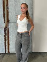 Modelfoto af pige der bærer Blakely top i hvid, samt grå Nanna jeans. Alt fra BySofieSønderby