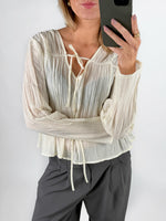 Modelfoto af pige i cremefarvet BREA bluse og grå LISA bukser. Alt er fra BySofieSønderby.