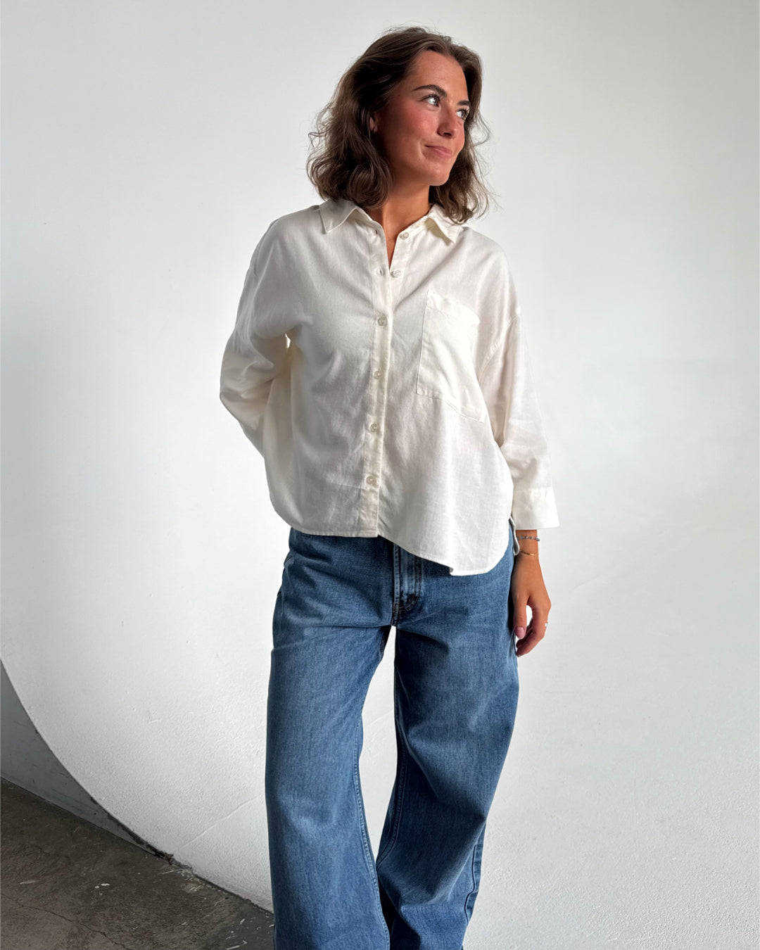 Modelfoto af pige som bærer en Breeze skjorte i hvid, samt et par blå Nanna jeans. Alt fra By Sofie Sønderby