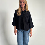 Modelfoto af pige som bærer en Breeze skjorte i sort, samt et par blå Nanna jeans. Alt fra By Sofie Sønderby