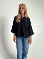 Modelfoto af pige som bærer en Breeze skjorte i sort, samt et par blå Nanna jeans. Alt fra By Sofie Sønderby