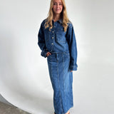 Modelfoto af pige som bærer en blå Cana denim jakke, samt Cana denim nederdel og sorte Carmen sandaler. Alt fra By Sofie Sønderby