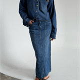 Modelfoto af pige som bærer en blå Cana denim nederdel, samt Cana denim jakke og sorte Carmen sandaler. Alt fra By Sofie Sønderby