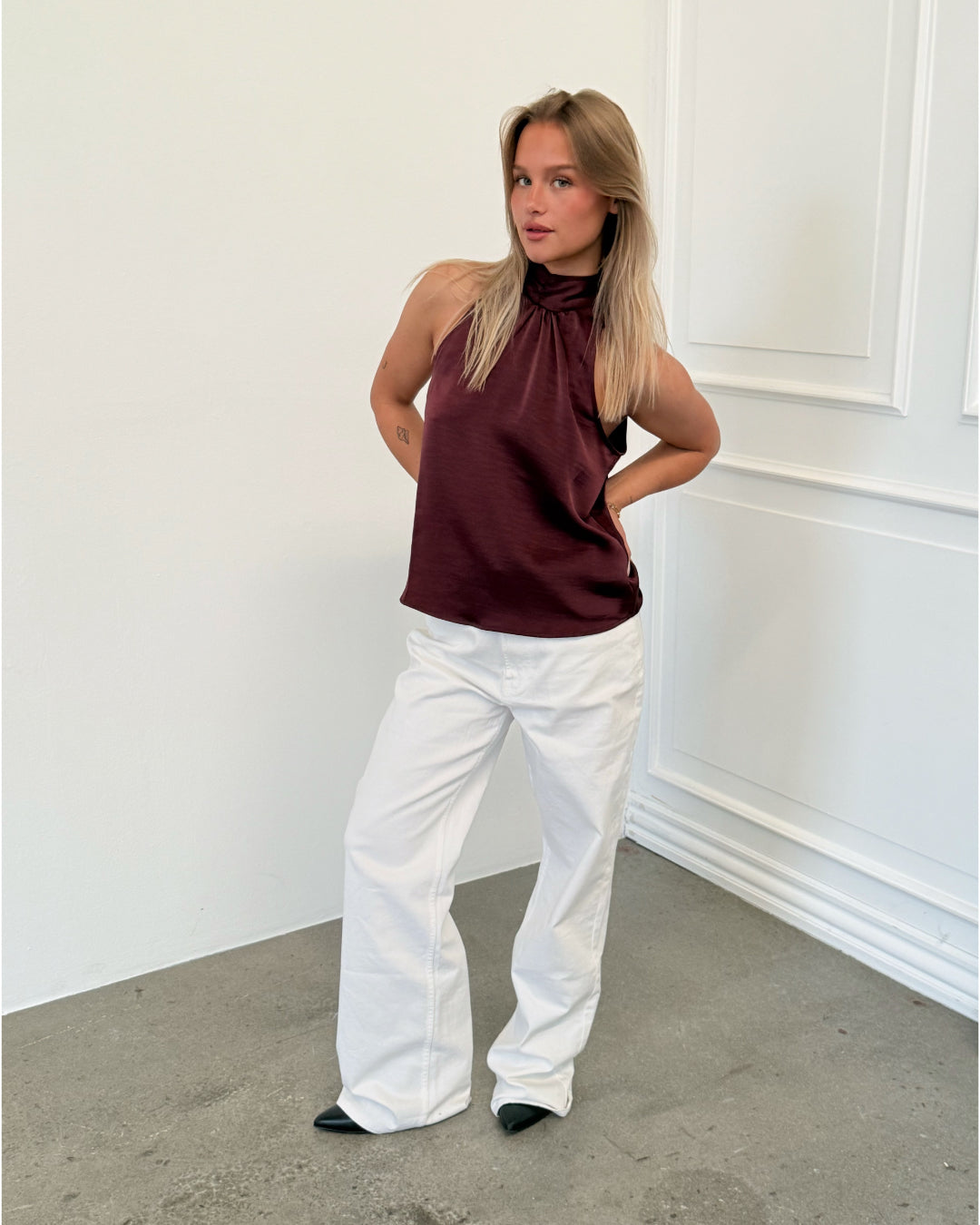 Modelfoto af pige i bordeaux CHILLI top, samt hvide NANNA jeans. Alt er fra BySofieSønderby.
