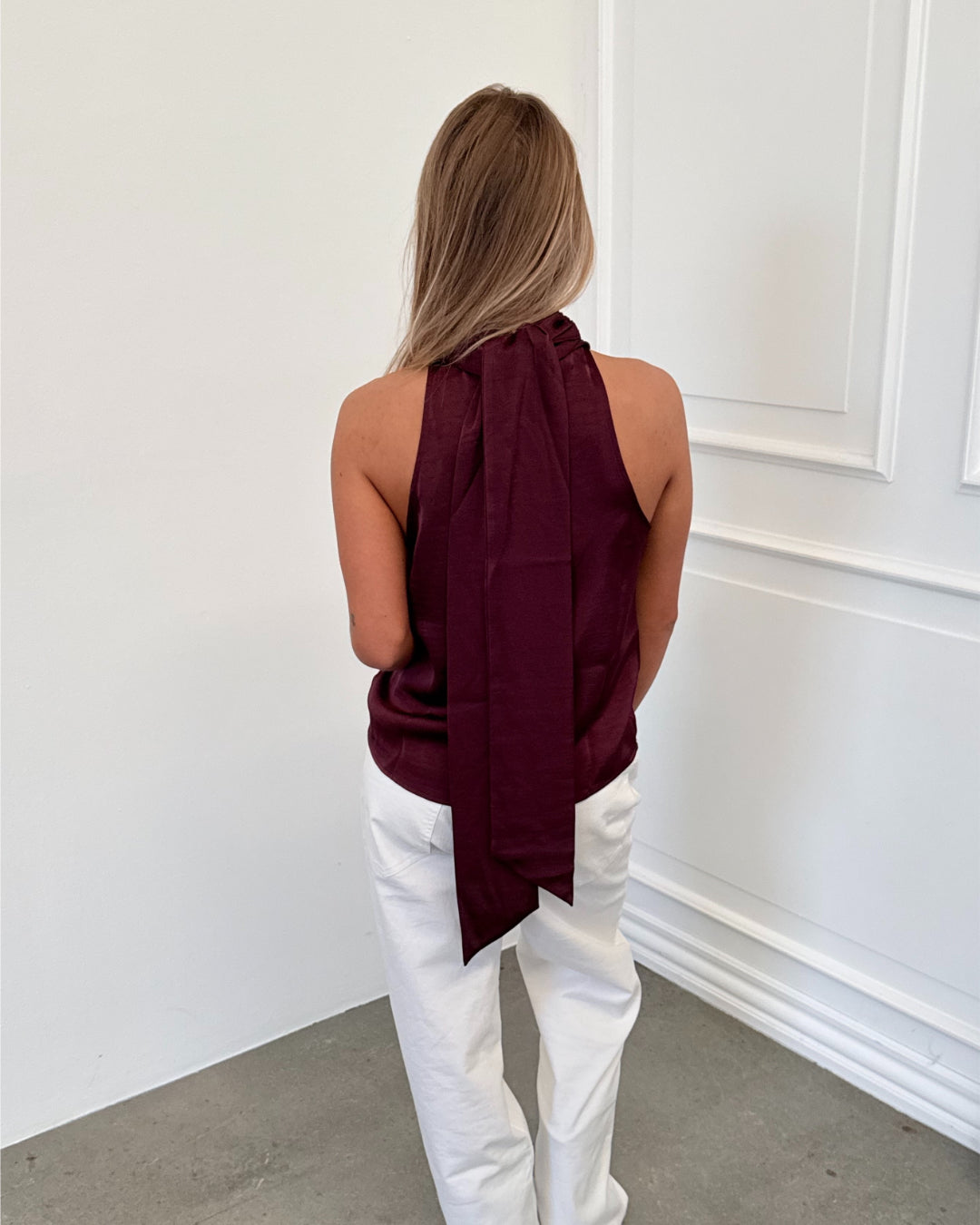 Modelfoto af pige i bordeaux CHILLI top, samt hvide NANNA jeans. Alt er fra BySofieSønderby.