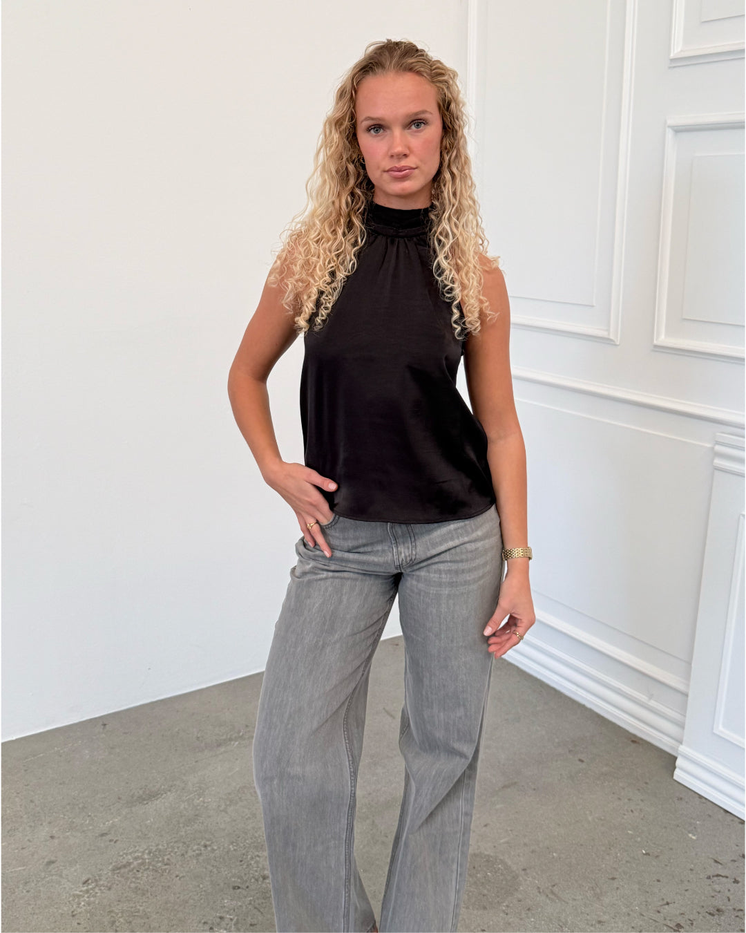 Modelfoto af pige i sort CHILLI top, samt grå NANNA jeans. Alt er fra BySofieSønderby.