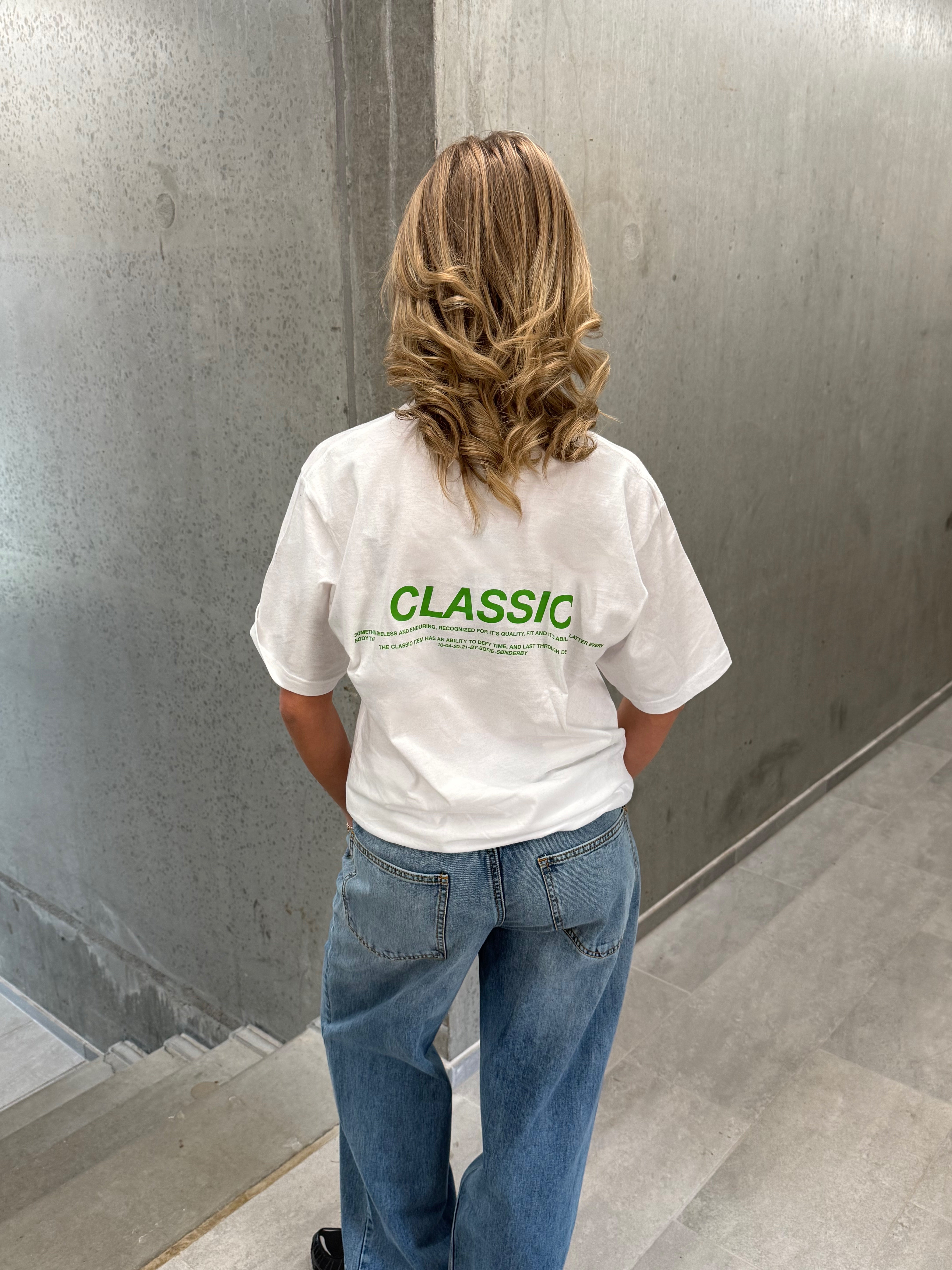Stemningsbillede af pige der bærer en hvid t-shirt med grønt classic tryk og blå NANNA jeans.  Fra BySofieSønderby