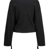 Sort sweater med lange ærmer hænger i stilling. Ærmerne har bindebånd ved manchetterne. Baggrunden er neutral, uden visuelle elementer.