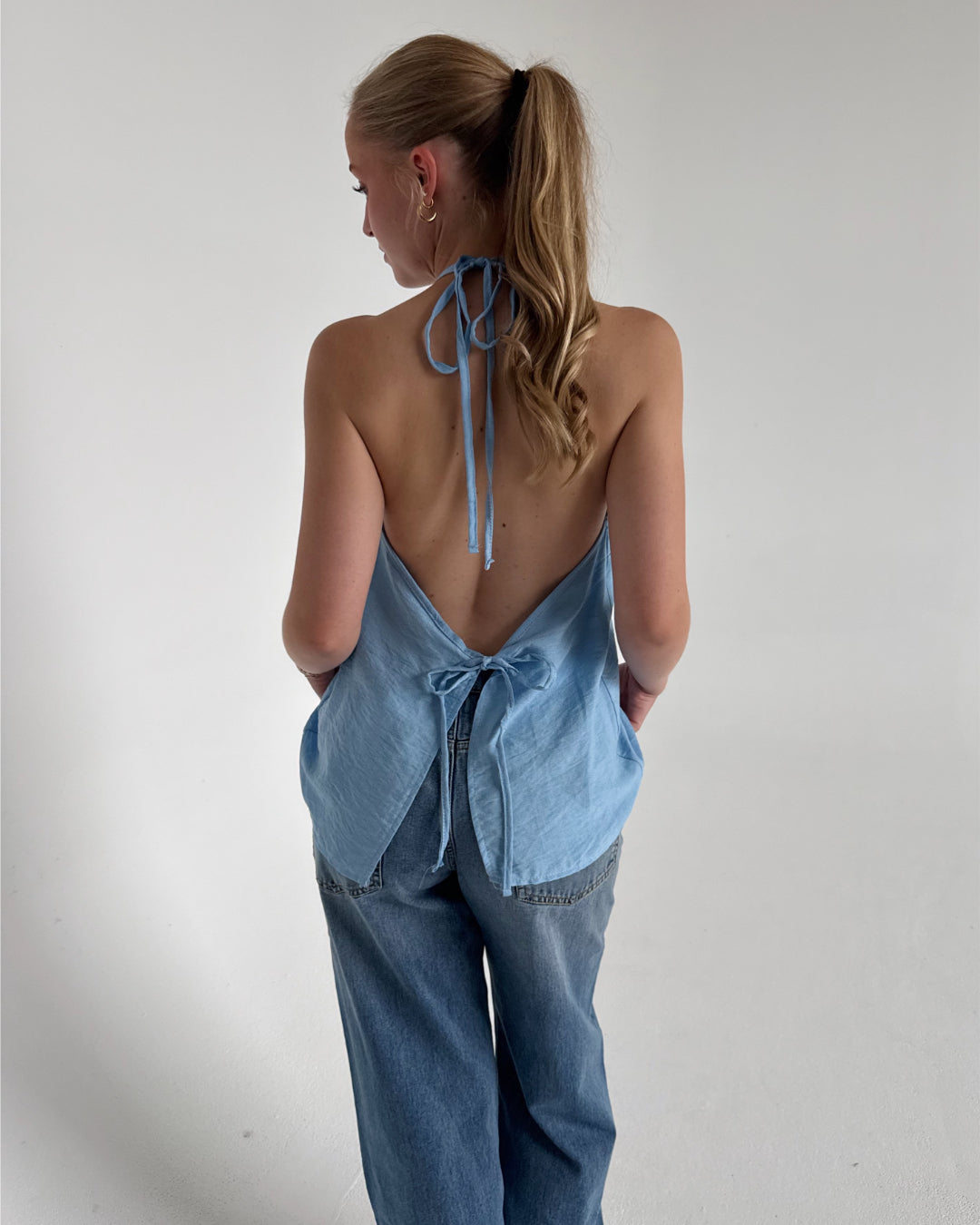 Modelfoto af pige som bærer en Daisy top i blå, samt et par Nanna jeans. Alt fra By Sofie Sønderby