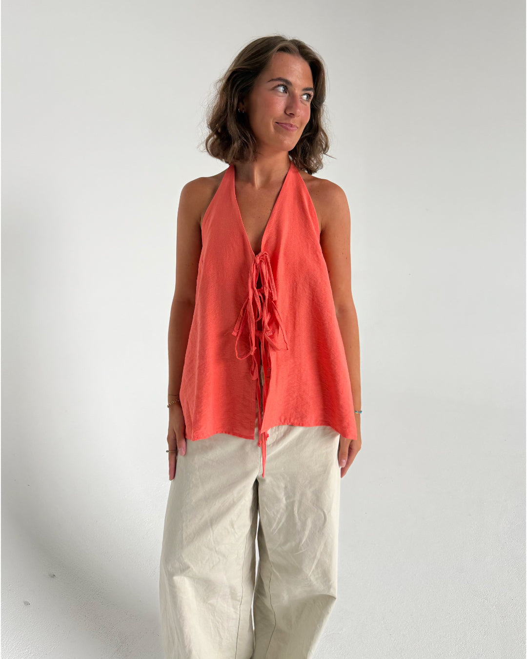 Modelfoto af pige som bærer en Daisy top i coral, samt et par beige Yale bukser. Alt fra By Sofie Sønderby