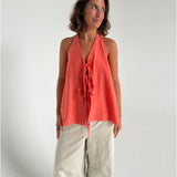 Modelfoto af pige som bærer en Daisy top i coral, samt et par beige Yale bukser. Alt fra By Sofie Sønderby