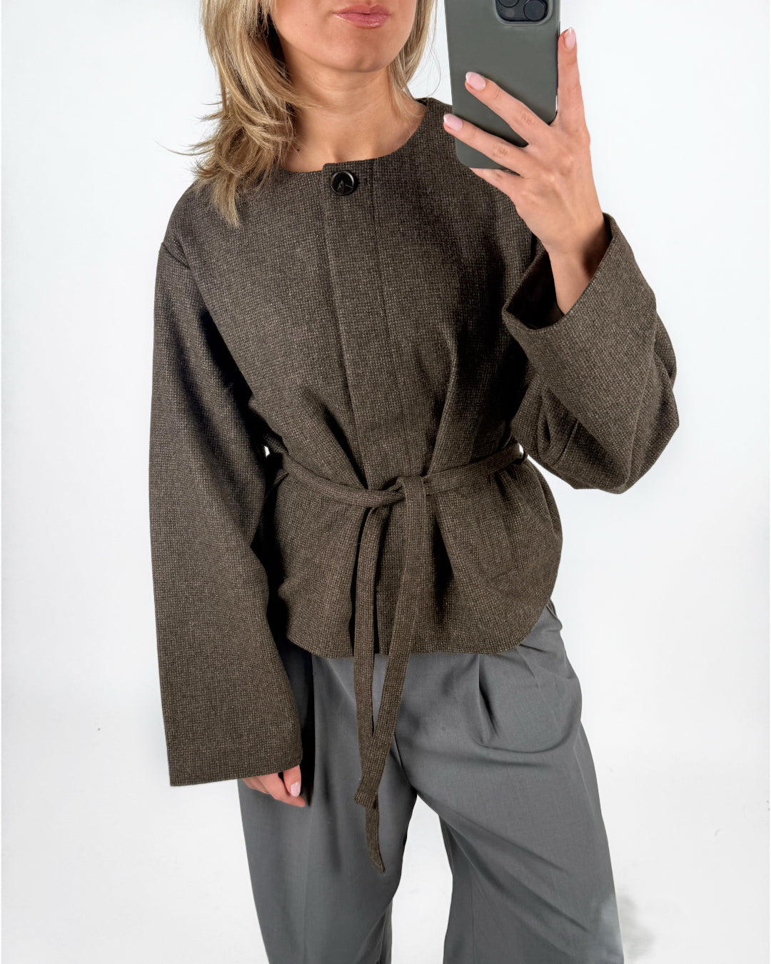 Modelfoto af pige i brun DARLA jakke med bindebånd, samt grå LISA bukser. Alt er fra BySofieSønderby.