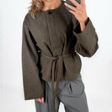 Modelfoto af pige i brun DARLA jakke med bindebånd, samt grå LISA bukser. Alt er fra BySofieSønderby.