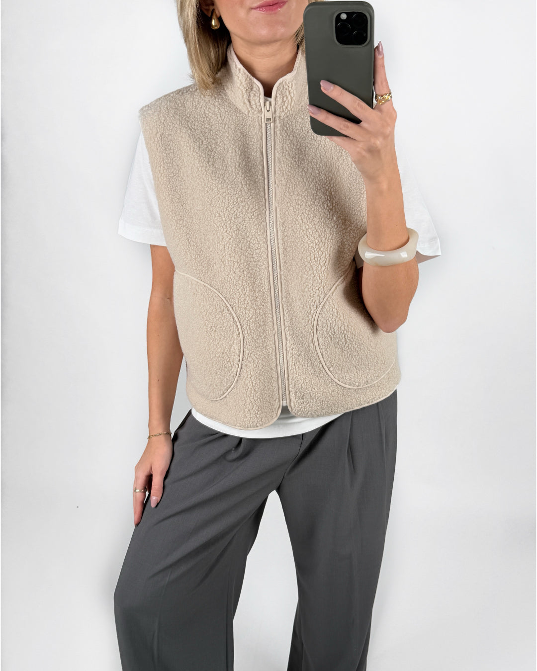 Modelfoto af pige i beige DAWN vest, hvid t-shirt og grå LISA bukser. Alt er fra BySofieSønderby.