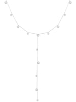 Halskæde med små kugler hænger elegant. Den er formet som et "Y" med kugler jævnt fordelt langs kæden. Baggrunden er lys, hvilket fremhæver det smykkende design.