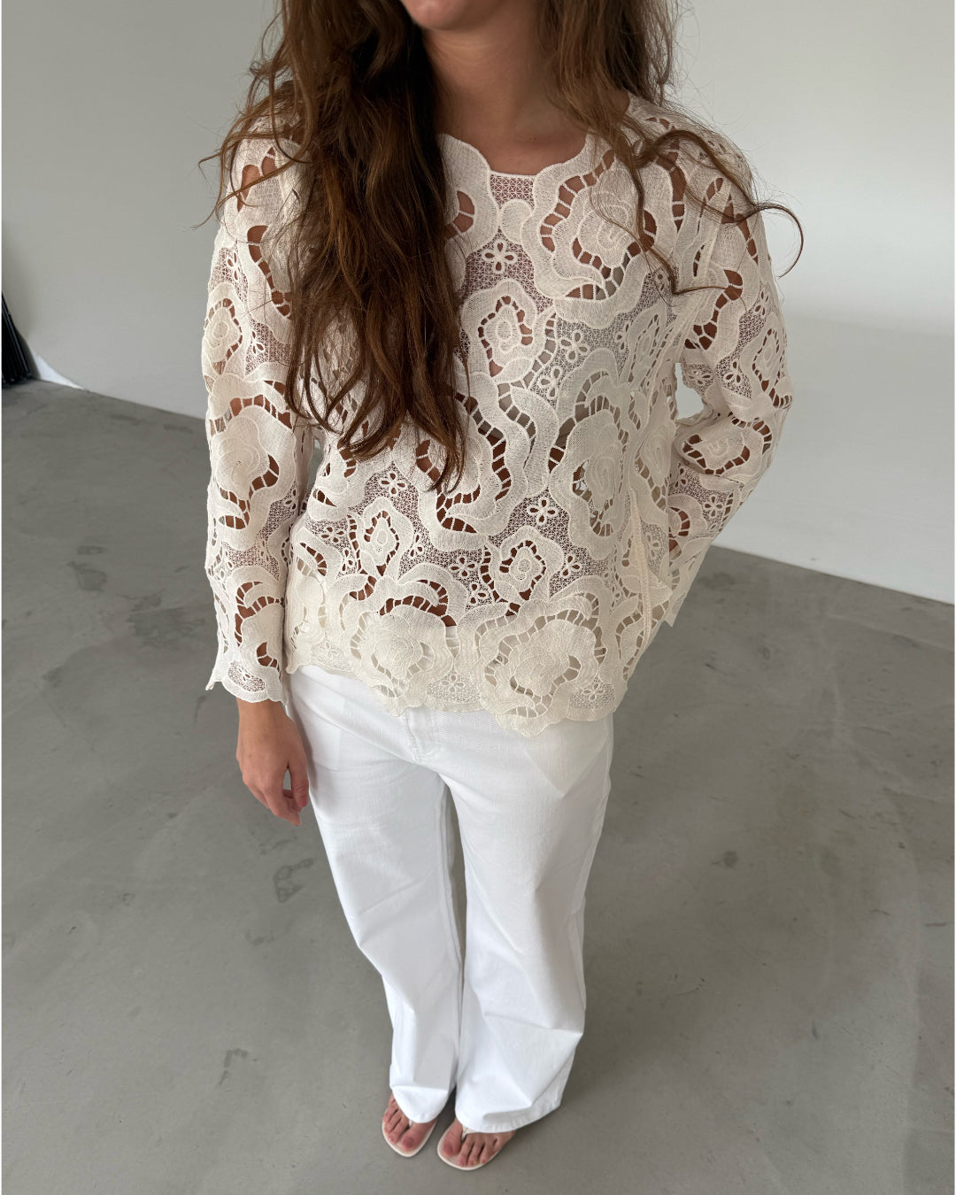 Modelfoto af pige som bærer hvid DOLLY bluse med storblomstret mønster, samt hvide jeans. Alt er fra BySofieSønderby