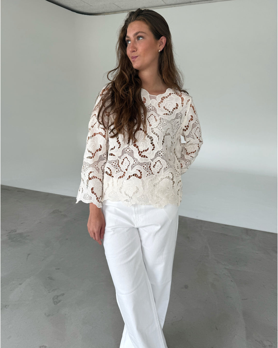 Modelfoto af pige som bærer hvid DOLLY bluse med storblomstret mønster, samt hvide jeans. Alt er fra BySofieSønderby