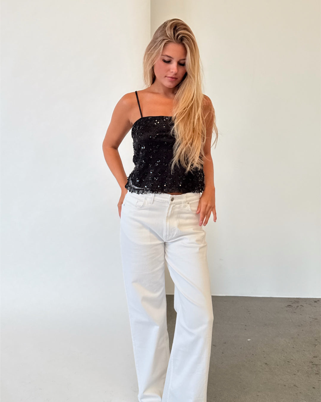 Modelfoto af pige i sort DREAM strop top, samt hvide NANNA jeans. Alt er fra BySofieSønderby.