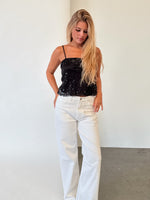 Modelfoto af pige i sort DREAM strop top, samt hvide NANNA jeans. Alt er fra BySofieSønderby.