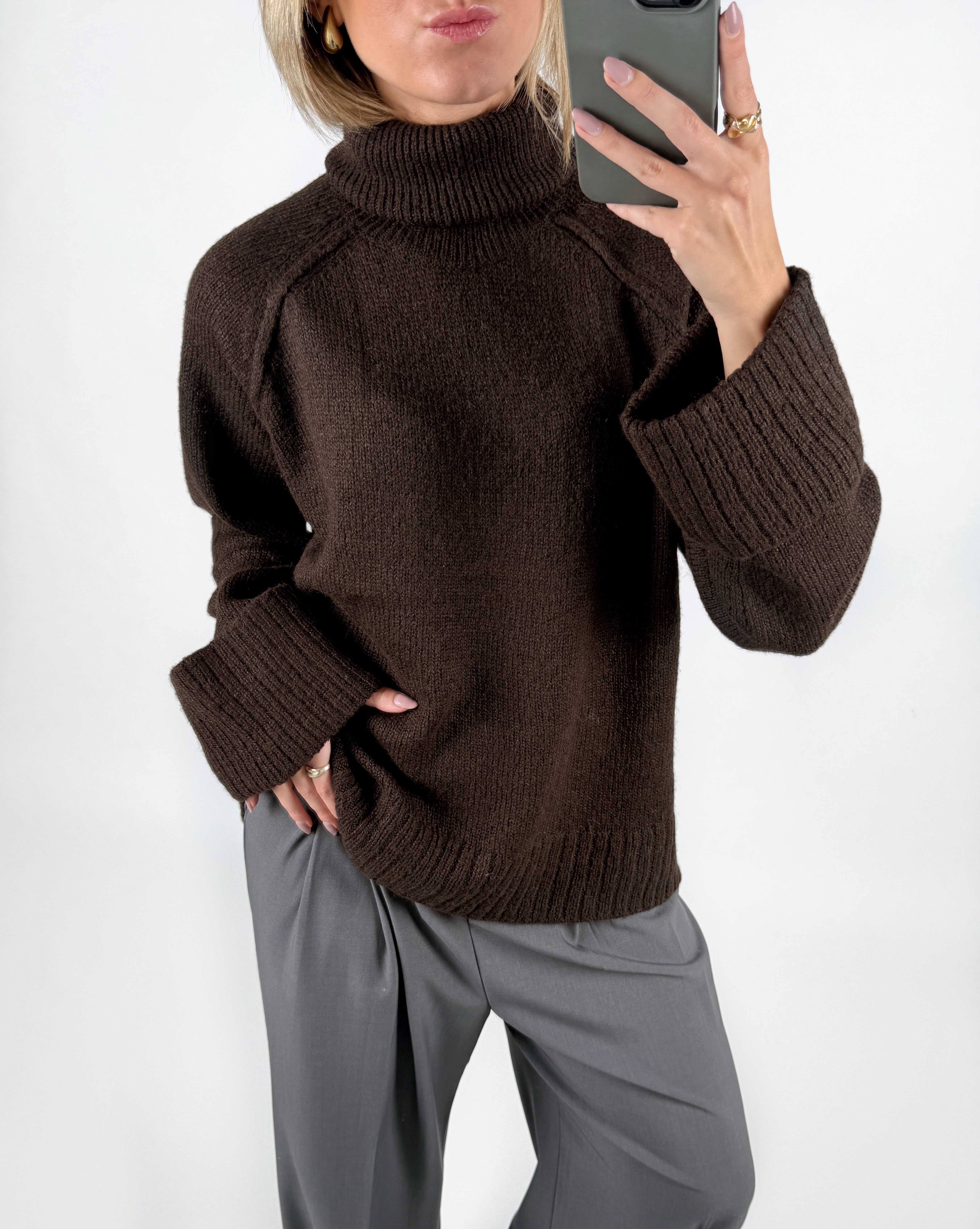 Modelfoto af pige i brun ELLINORA striktrøje med rullekrave, samt grå LISA bukser. Alt er fra BySofieSønderby.