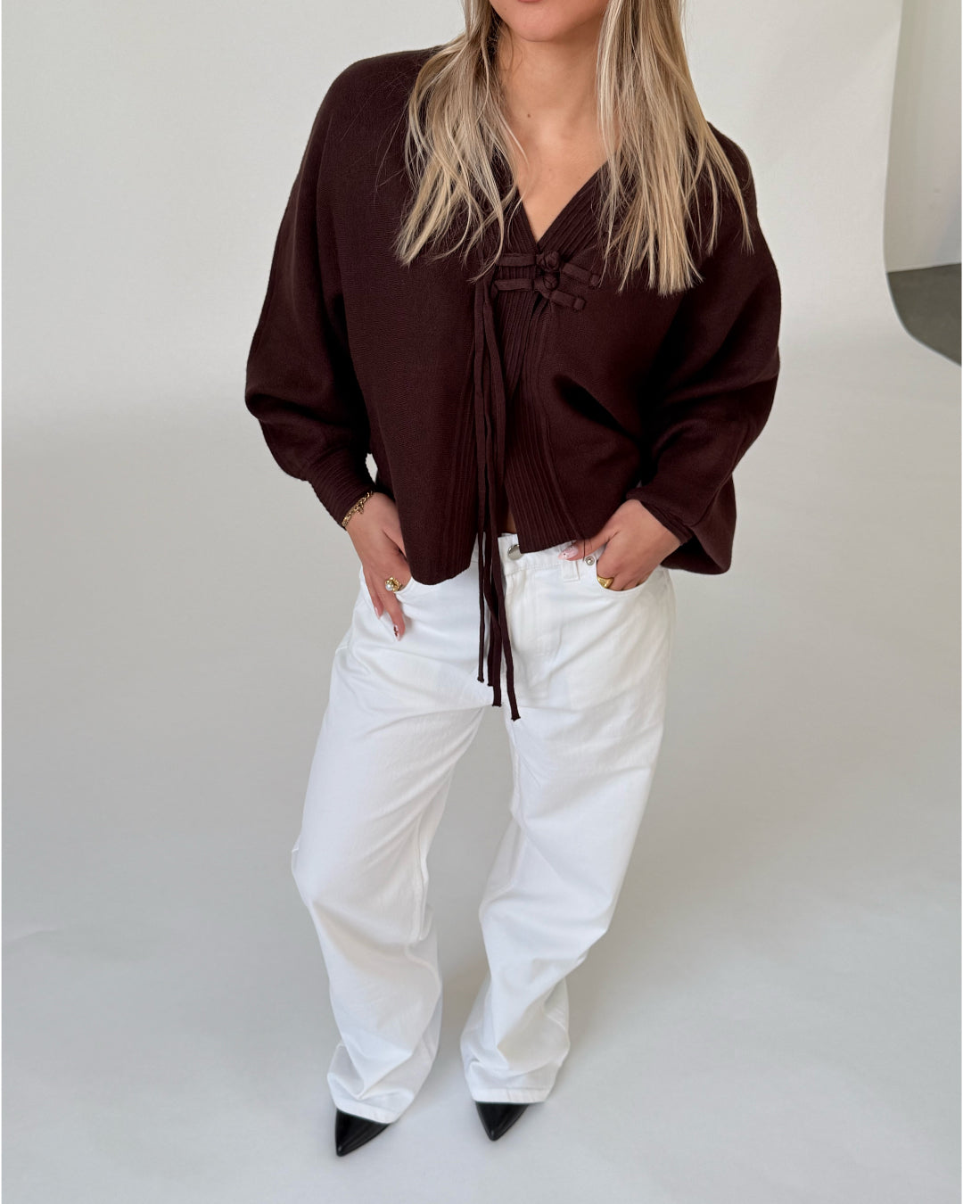 Modelfoto af pige i brun ELLIOT cardigan, samt hvide NANNA jeans. Alt er fra BySofieSønderby.