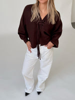 Modelfoto af pige i brun ELLIOT cardigan, samt hvide NANNA jeans. Alt er fra BySofieSønderby.