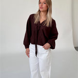 Modelfoto af pige i brun ELLIOT cardigan, samt hvide NANNA jeans. Alt er fra BySofieSønderby.