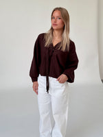 Modelfoto af pige i brun ELLIOT cardigan, samt hvide NANNA jeans. Alt er fra BySofieSønderby.