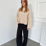 Modelfoto af pige i sort melerede ELLIS bukser, samt beige striktrøje. Alt er fra BySofieSønderby.