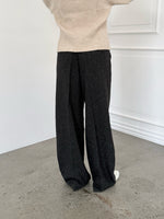 Modelfoto af pige i sort melerede ELLIS bukser, samt beige striktrøje. Alt er fra BySofieSønderby.