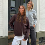 Modelfoto af 2 piger, som begge bærer en EMMA hoodie, brun og lysegrå. Dertil NANNA jeans, hvide og MILAN bukser, grå - alt fra BySofieSønderby
