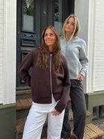 Modelfoto af 2 piger, som begge bærer en EMMA hoodie, brun og lysegrå. Dertil NANNA jeans, hvide og MILAN bukser, grå - alt fra BySofieSønderby