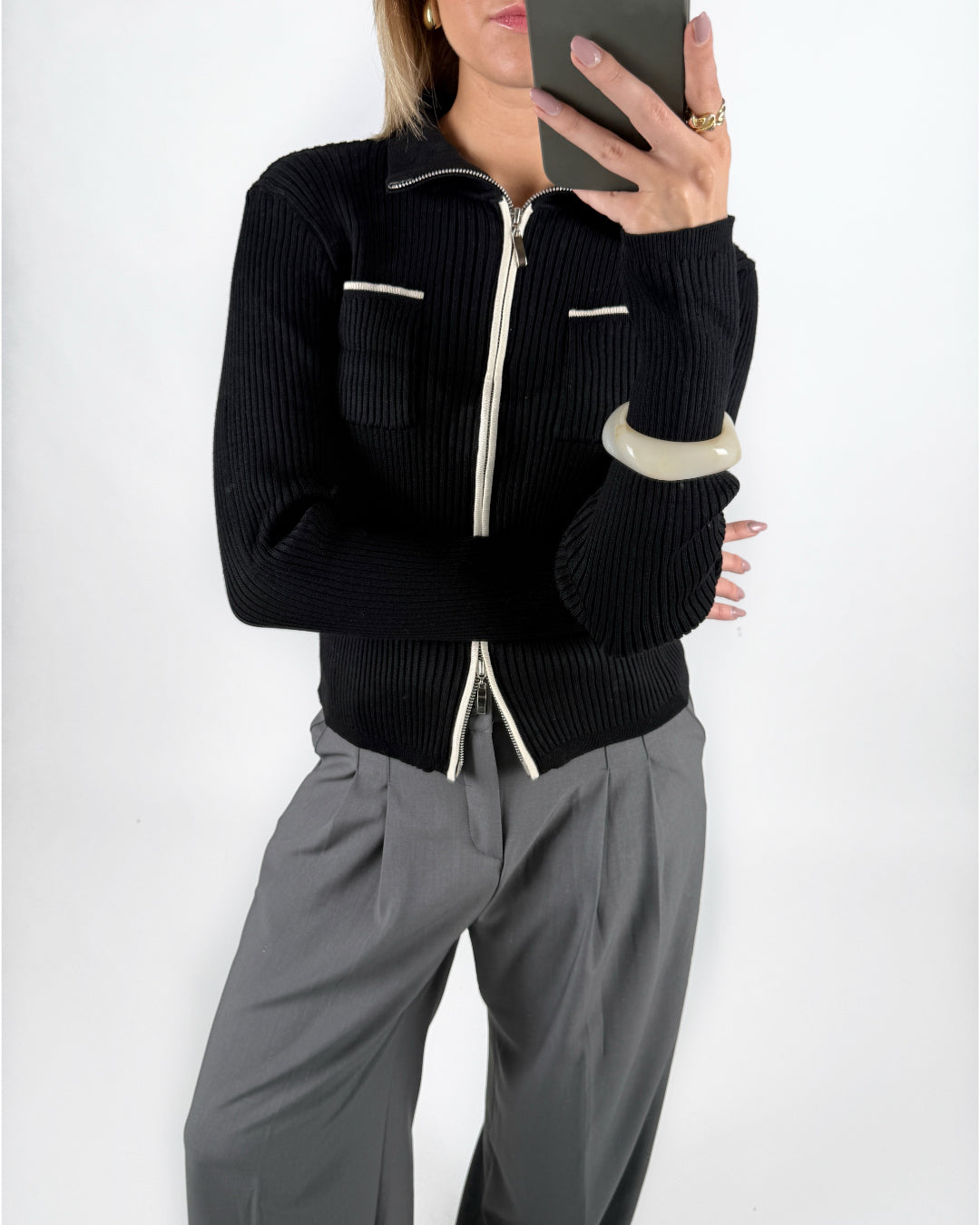 Modelfoto af pige i sort EMRYN zip-strik  og grå LISA bukser. Alt er fra BySofieSønderby.