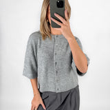 Modelfoto af pige i grå EVI strik t-shirt med knapper og grå LISA bukser. Alt er fra BySofieSønderby.