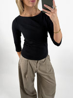 Stemningsbillede af pige der bærer en sort FIFI boatneck bluse, samt beige MONI bukser.  Fra BySofieSønderby