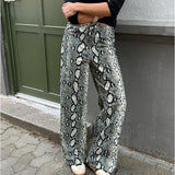 Modelfoto af pige i Gelly bukser med slangeprint, og en sort bluse. Alt er fra BySofieSønderby