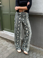 Modelfoto af pige i Gelly bukser med slangeprint, og en sort bluse. Alt er fra BySofieSønderby