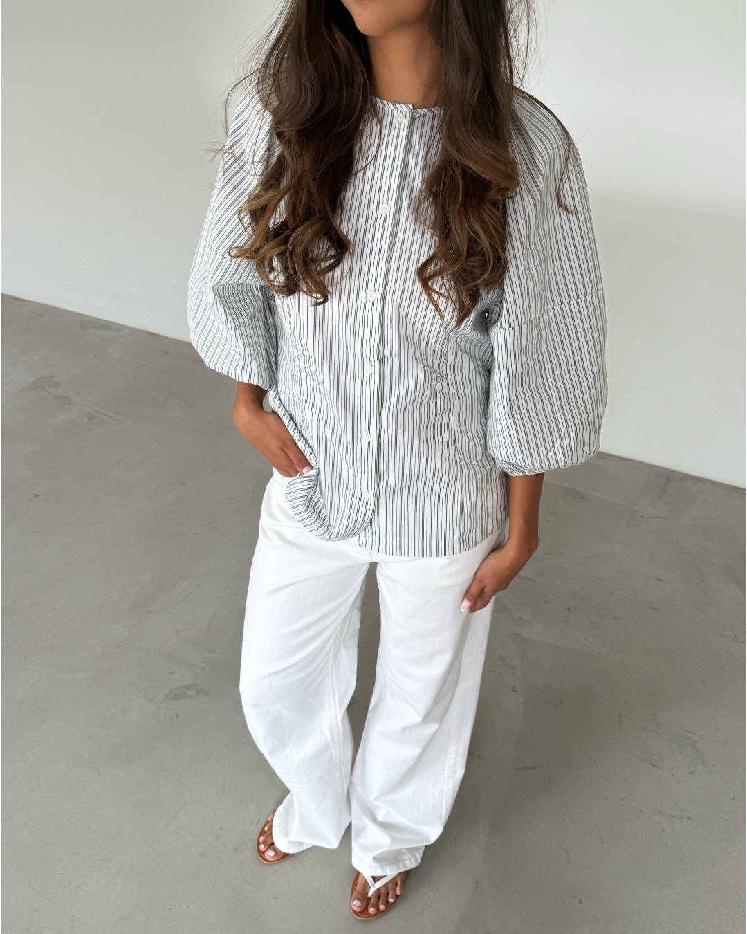 Modelfoto af pige som bærer grøn-hvid stribet HELEN skjorte  og hvide jeans. Alt er fra BySofieSønderby