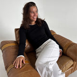 Modelfoto af pige som bærer en langærmet Henna bluse i sort, samt hvide Nanna jeans. Alt fra By Sofie Sønderby